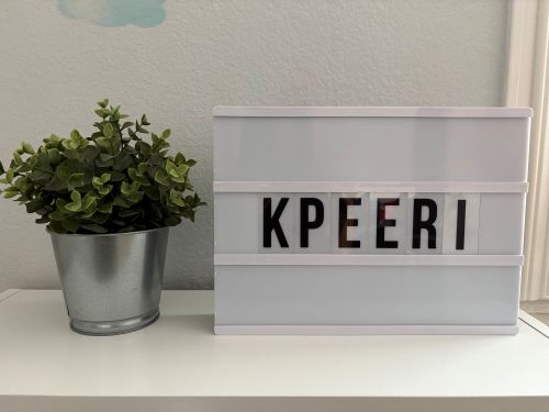 KPEERI box sign and plant on top of a bookshelf