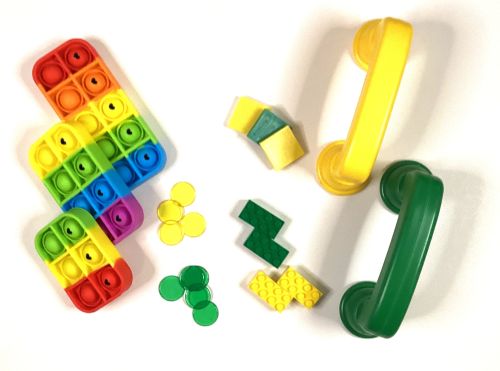 Multicolored bubble sound poppers, legos, plastic chips, square tiles, and sound phones.